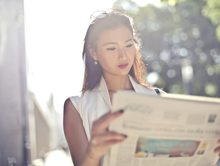 woman reading the newspaper. how to place legal notice in newspaper or online