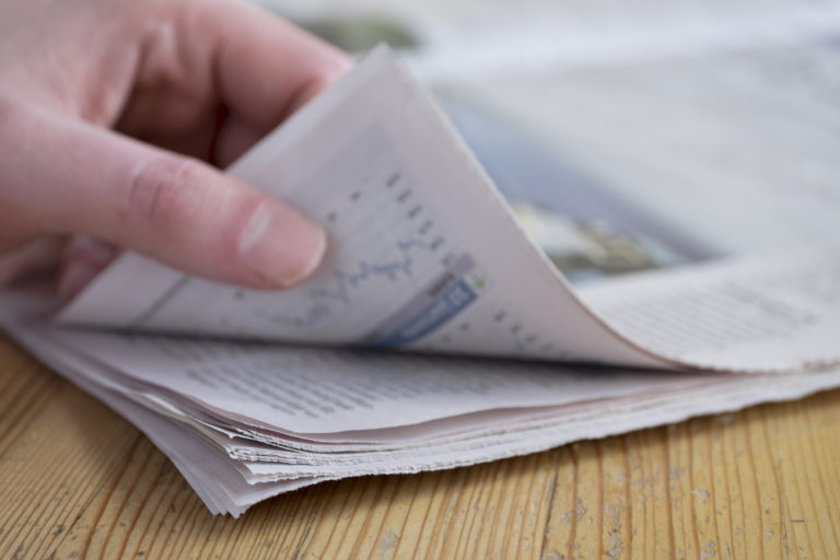 person thumbing through a newspaper labor certification advertising requirements place legal ads legal notice ad in the newspaper