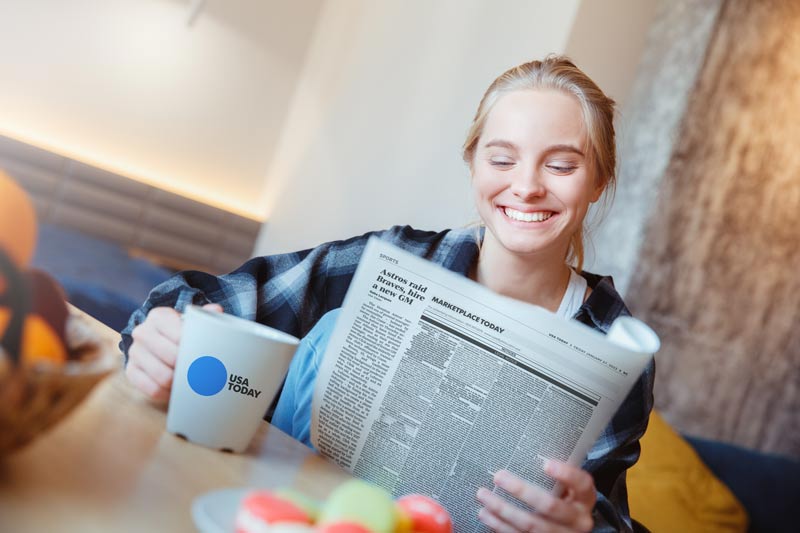 blonde woman reading a newspaper with a copy cup. buy advertising in advertising groups 