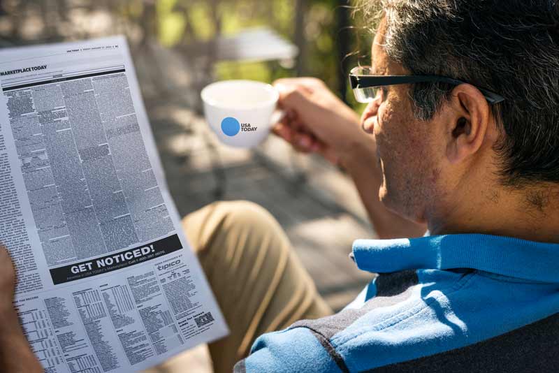 man reading a newspaper holding a coffee cup place discount newspaper advertising options